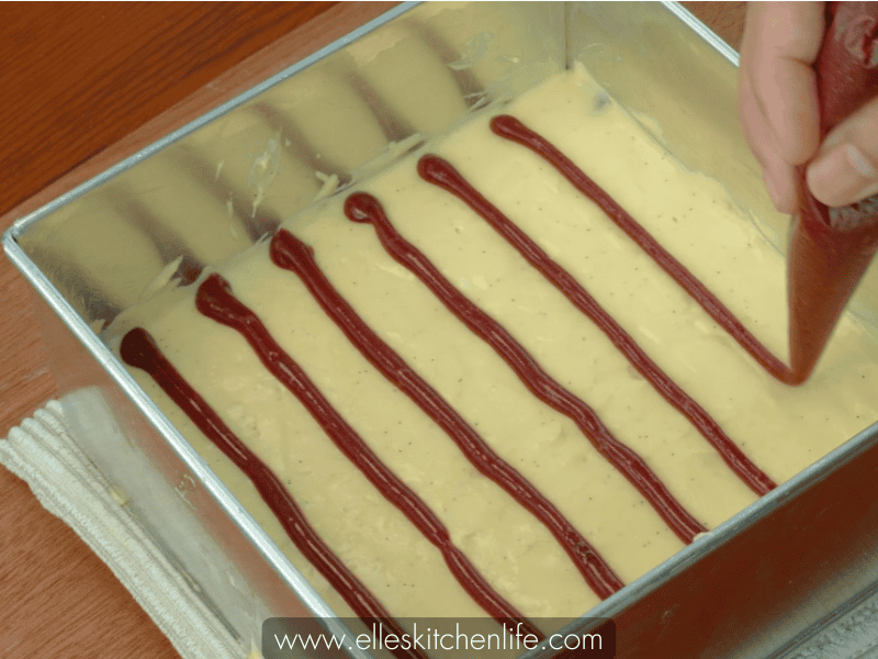 Squeezing red velvet batter on top of cream cheese layer