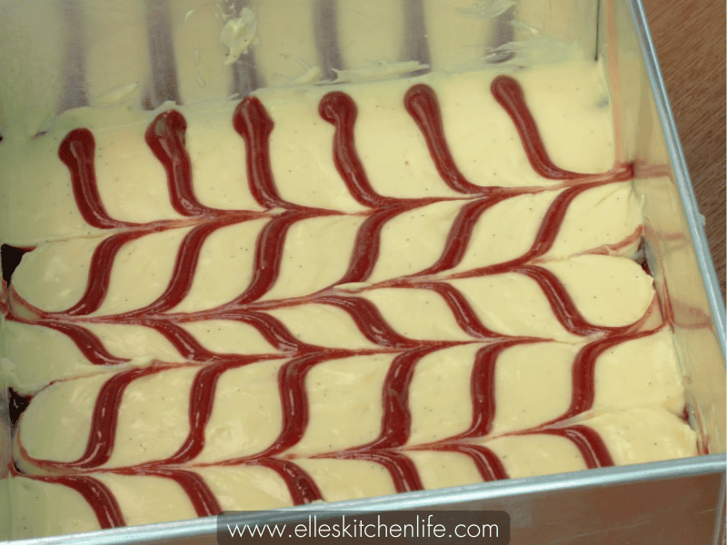 Swirling red velvet batter into cream cheese layer to create patterns