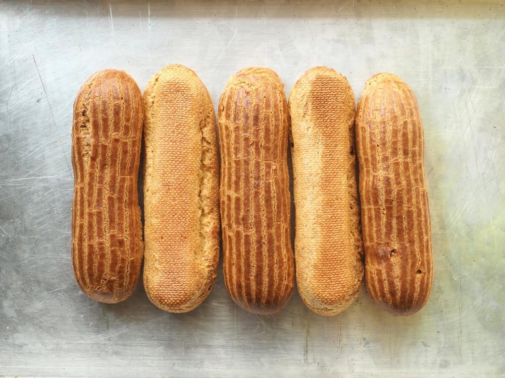 Perfectly golden-brown éclairs cooling on a wire rack