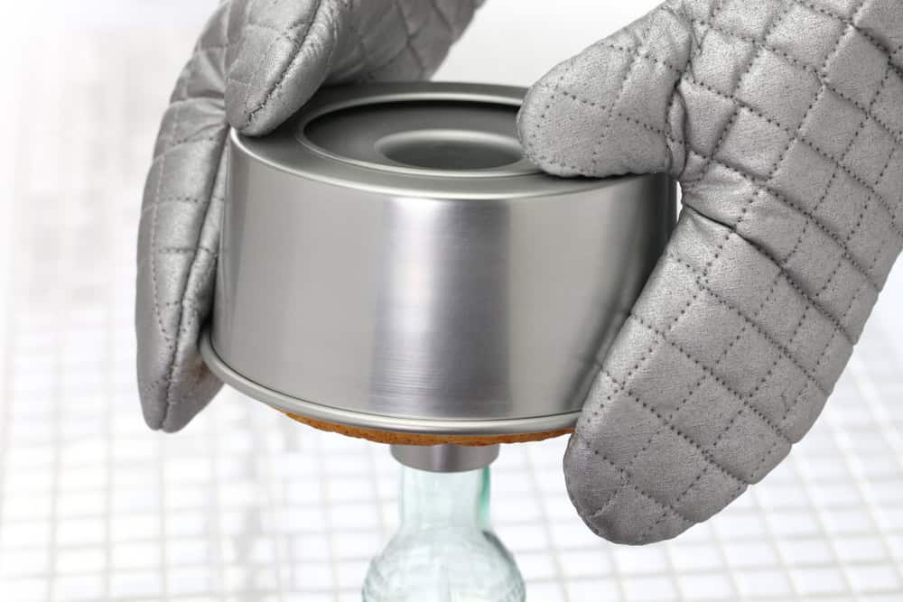 A chiffon cake cooling upside down on a bottle to prevent collapsing.