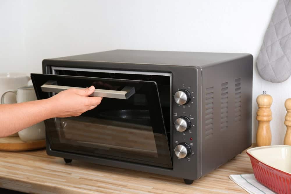 An open oven door revealing a partially baked cake, which can cause it to collapse.