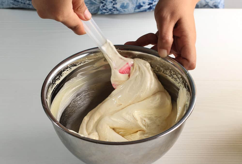 A baker gently folding whipped egg whites into cake batter to maintain airiness.