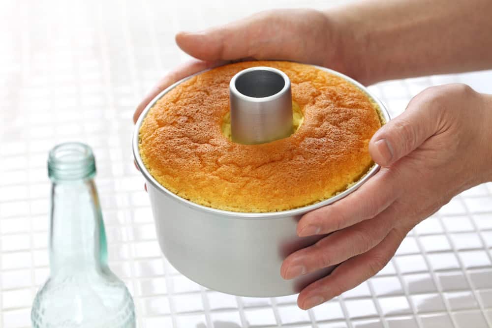 A chiffon cake baking in a tube pan, which helps with even rising.