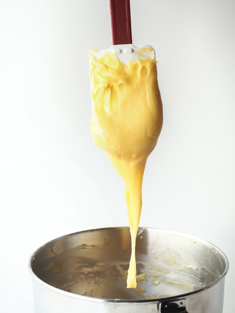 A baker lifting choux pastry with a spatula, forming a smooth 'V' shape